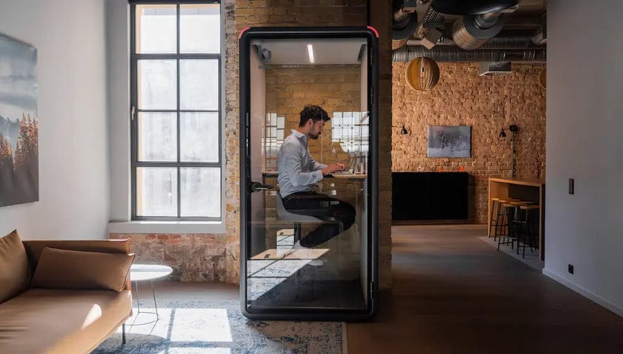 Person working on a laptop inside a Bureau One booth in a loft office
