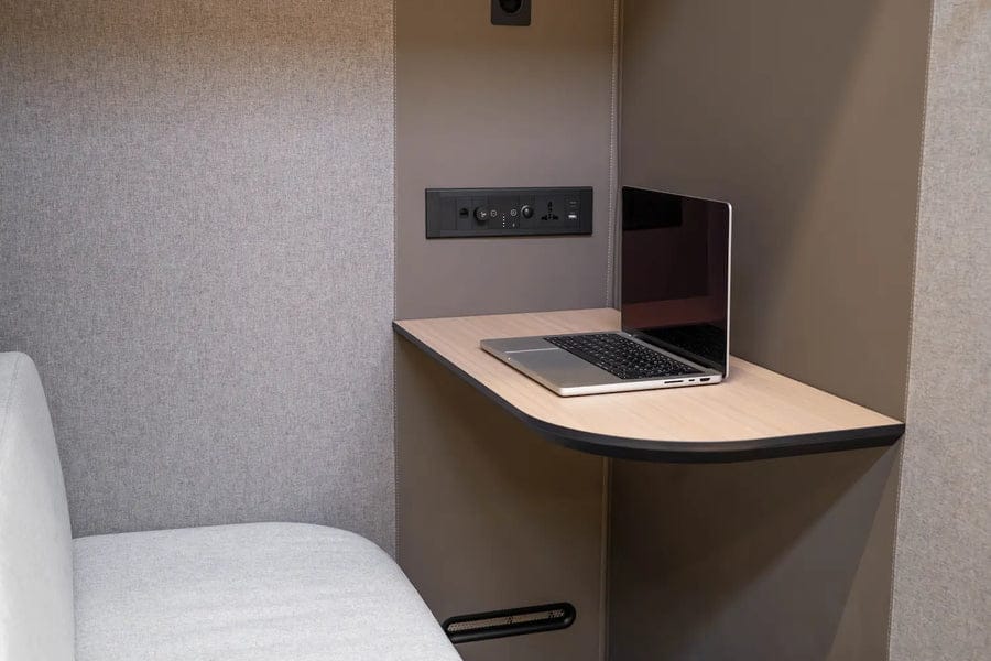 Inside a Bureau Tuesday pod: fold-down desk with a laptop and a bench seat