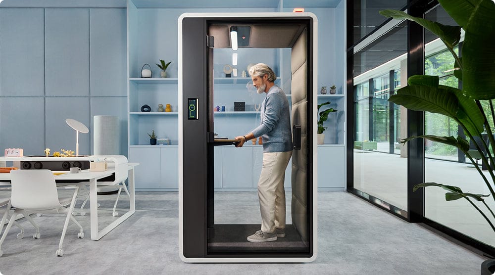 hushFree.S office pod in an open-plan office, with a person standing at the raised desk